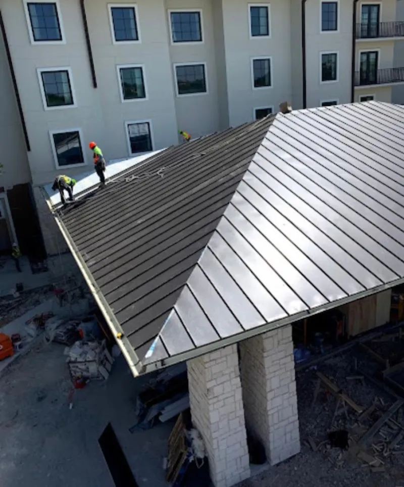 Crew installing standing seam metal roof panels on a commercial project in Oxnard
